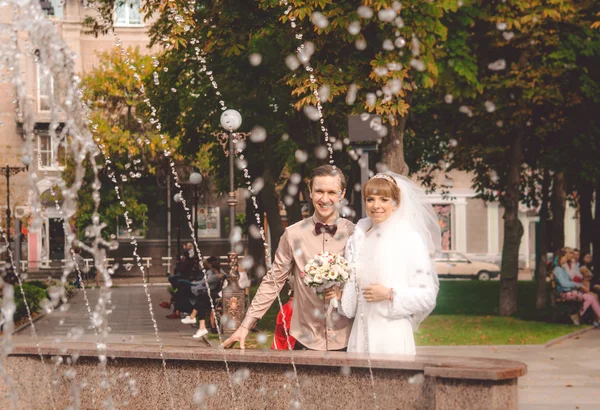 有趣的喷雾剂的喷泉和一对年轻夫妇的新婚夫妇 — 图库照片