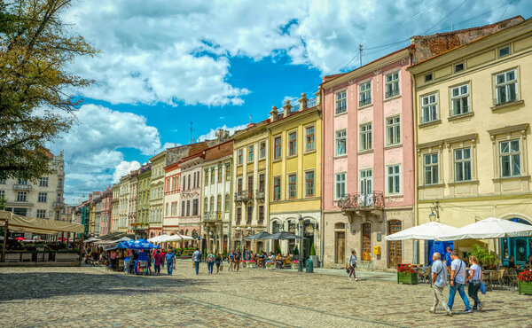 Lviv, Ukraine - August 30, 2019: Tourists strolling along Market Square in the city of Lviv, Ukraine. A sunny summer day in a famous old tourist town in Eastern Europe. Ancient houses and restaurants