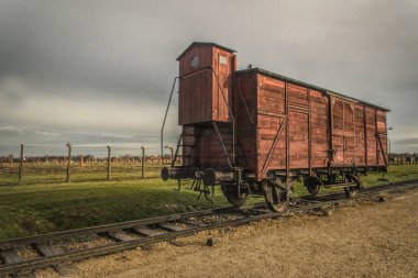 Auschwitz, Polonya - 29 Kasım 2019: eski ahşap yük vagonu ve demiryolu dikenli tellerin ve kışlaların arka planına karşı. Yahudi ve savaş esirlerinin Polonya 'daki Auschwitz toplama kampına nakledilmesi. Nazi terörü 
