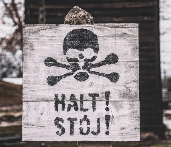 Auschwitz, Poland - November 29, 2019: Hazard warning street sign - skull and crossbones. Barbed wire and live wires in the Nazi concentration camp Auschwitz in Poland. Memorial and Museum of Nazi Terror and the Holocaust in Europe