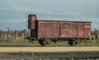 Auschwitz, Polonya - 29 Kasım 2019: eski ahşap yük vagonu ve demiryolu dikenli tellerin ve kışlaların arka planına karşı. Yahudi ve savaş esirlerinin Polonya 'daki Auschwitz toplama kampına nakledilmesi. Nazi terörü 