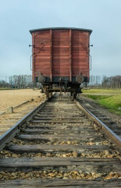 Auschwitz, Polonya - 29 Kasım 2019: eski ahşap yük vagonu ve demiryolu dikenli tellerin ve kışlaların arka planına karşı. Yahudi ve savaş esirlerinin Polonya 'daki Auschwitz toplama kampına nakledilmesi. Nazi terörü 