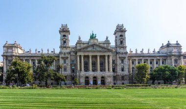 Budapest / Hungary - August 29 2019: Facade of the historic luxury building of the Ethnographic Museum in Budapest, Hungary. Ancient building with columns against the blue sky and green city park