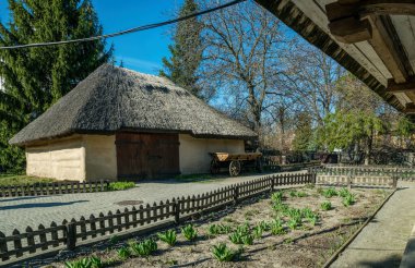 Bahçenin arka bahçesindeki eski geleneksel köy evi. Beyaz kil duvarlar ve tahta çatı