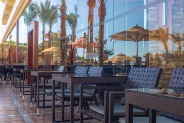 Sharm el Sheikh / Mısır - 3 Aralık 2019: Mısır 'ın Sharm El Sheikh kentindeki bir tatil köyünde güneş havuzu yakınlarındaki bir restoranın masa ve sandalyeleri. Sahil tatili ve servis hepsi dahil.