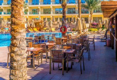 Sharm el Sheikh / Mısır - 3 Aralık 2019: Mısır 'ın Sharm El Sheikh kentindeki bir tatil köyünde güneş havuzu yakınlarındaki bir restoranın masa ve sandalyeleri. Sahil tatili ve servis hepsi dahil.
