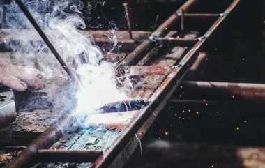Köy evinin avlusundaki atölye ve garaj. Usta eski usul kaynak makinesinde metal kaynaklarla kaynak yapıyor. Tamir, el işi ve inşaat.