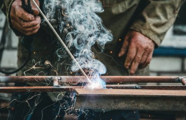 Köy evinin avlusundaki atölye ve garaj. Usta eski usul kaynak makinesinde metal kaynaklarla kaynak yapıyor. Tamir, el işi ve inşaat.