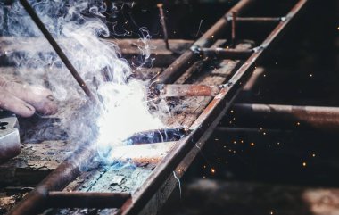 Eski köy kaynak atölyesi. Metal ve kaynak elektrotlarıyla çalışan yaşlı bir adam.