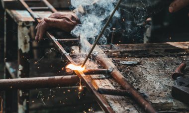 Eski köy kaynak atölyesi. Metal ve kaynak elektrotlarıyla çalışan yaşlı bir adam.