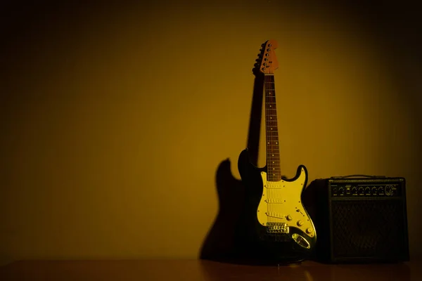 Guitarra elétrica de luz amarela na frente de uma parede vintage — Fotografia de Stock