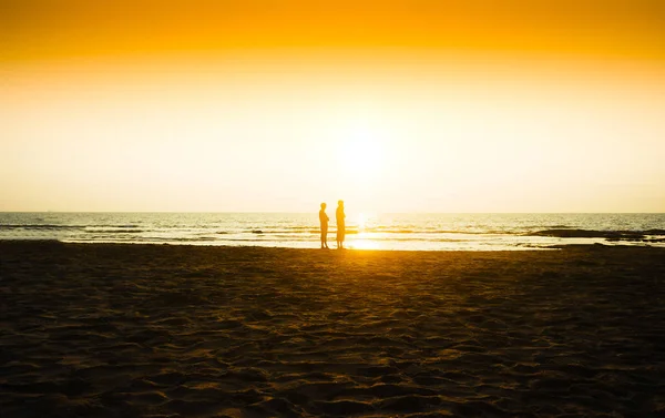 Dois amigos encontrando o pôr do sol no fundo da praia do oceano — Fotografia de Stock