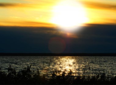 Nehirde dramatik bir günbatımı ve ışık sızıntısı