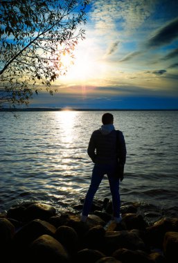 Dramatik göl batımı arka planı izleyen adam