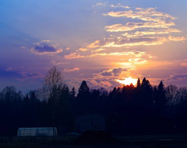 Köy çiftliğinin arka planında gün batımı yanıyor