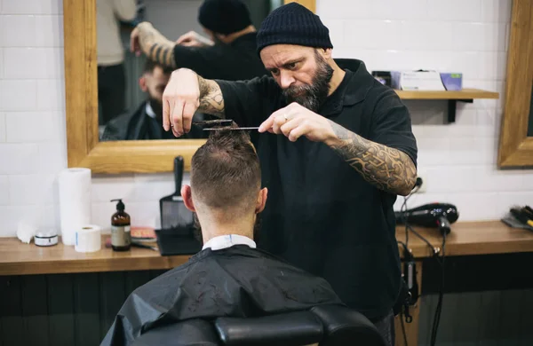 Homem barbudo cortando cabelo e barba no barbeiro local — Fotografia de Stock