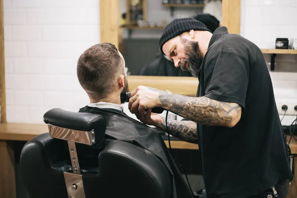 Homem barbudo cortando cabelo e barba no barbeiro local — Fotografia de Stock