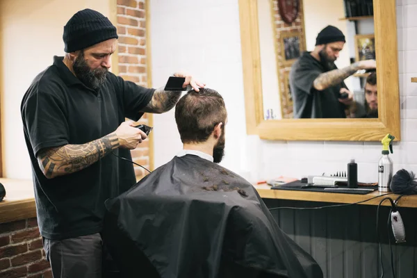 Homem barbudo cortando cabelo e barba no barbeiro local — Fotografia de Stock