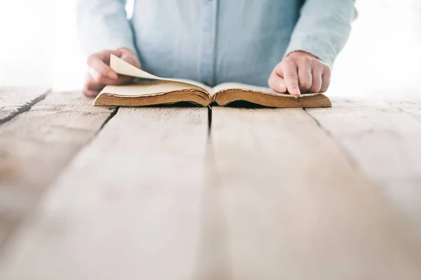 Ruce modlí s biblí nad dřevěným stolem — Stock fotografie