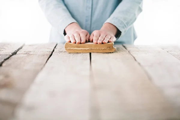 Hands praying with a bible over wooden table — Stock Photo, Image