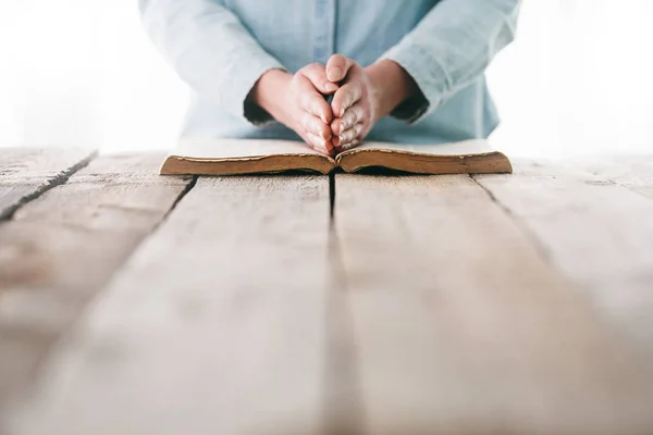 Ellerin ahşap masanın üzerinde İncil 'le dua ediyor. — Stok fotoğraf
