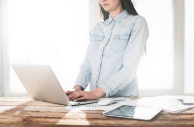 Ahşap bir stand üzerine kapalı dizüstü ve tablet pc üzerinde çalışan kadın