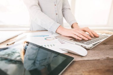 Ahşap bir stand üzerine kapalı dizüstü ve tablet pc üzerinde çalışan kadın