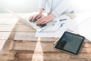 Ahşap bir stand üzerine kapalı dizüstü ve tablet pc üzerinde çalışan kadın