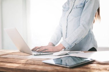 Ahşap bir stand üzerine kapalı dizüstü ve tablet pc üzerinde çalışan kadın