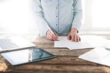 Ahşap bir stand üzerine kapalı dizüstü ve tablet pc üzerinde çalışan kadın