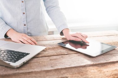 Ahşap bir stand üzerine kapalı dizüstü ve tablet pc üzerinde çalışan kadın