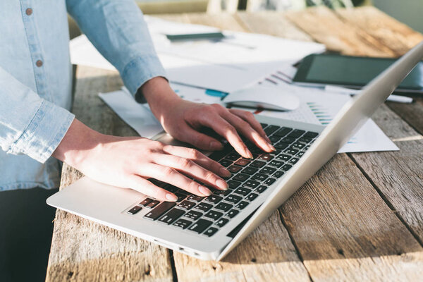 Woman working on a laptop and tablet pc indoor on a wooden stand