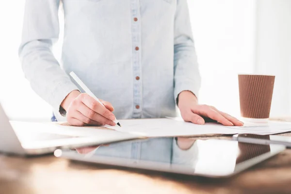 Woman working on a laptop and tablet pc indoor on a wooden stand — Stock Photo, Image