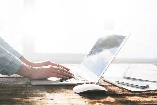 Frau arbeitet drinnen an Laptop und Tablet-PC auf einem Holzständer — Stockfoto