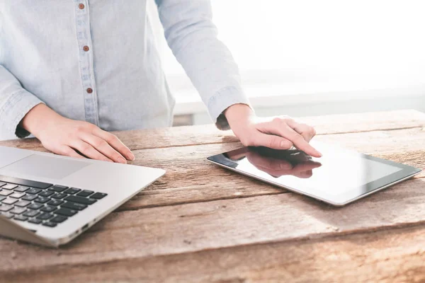 Mujer trabajando en un ordenador portátil y tableta PC interior en un soporte de madera — Foto de Stock