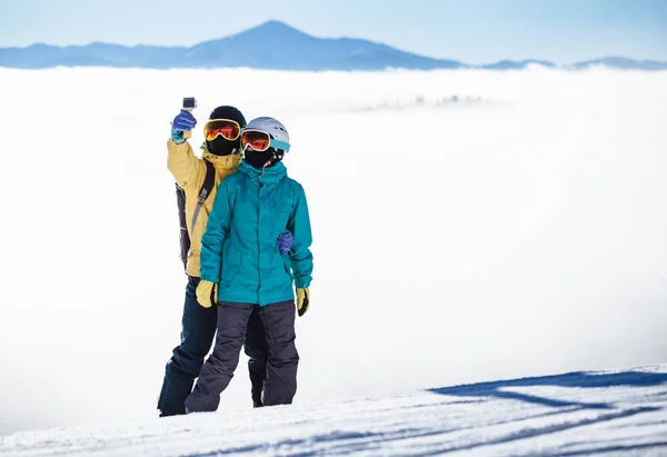 Skifahrer fotografieren sich mit Smartphone über einem Berg — Stockfoto