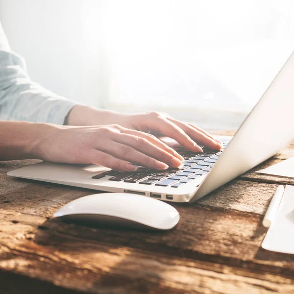 Frau arbeitet drinnen an Laptop und Tablet-PC auf einem Holzständer — Stockfoto