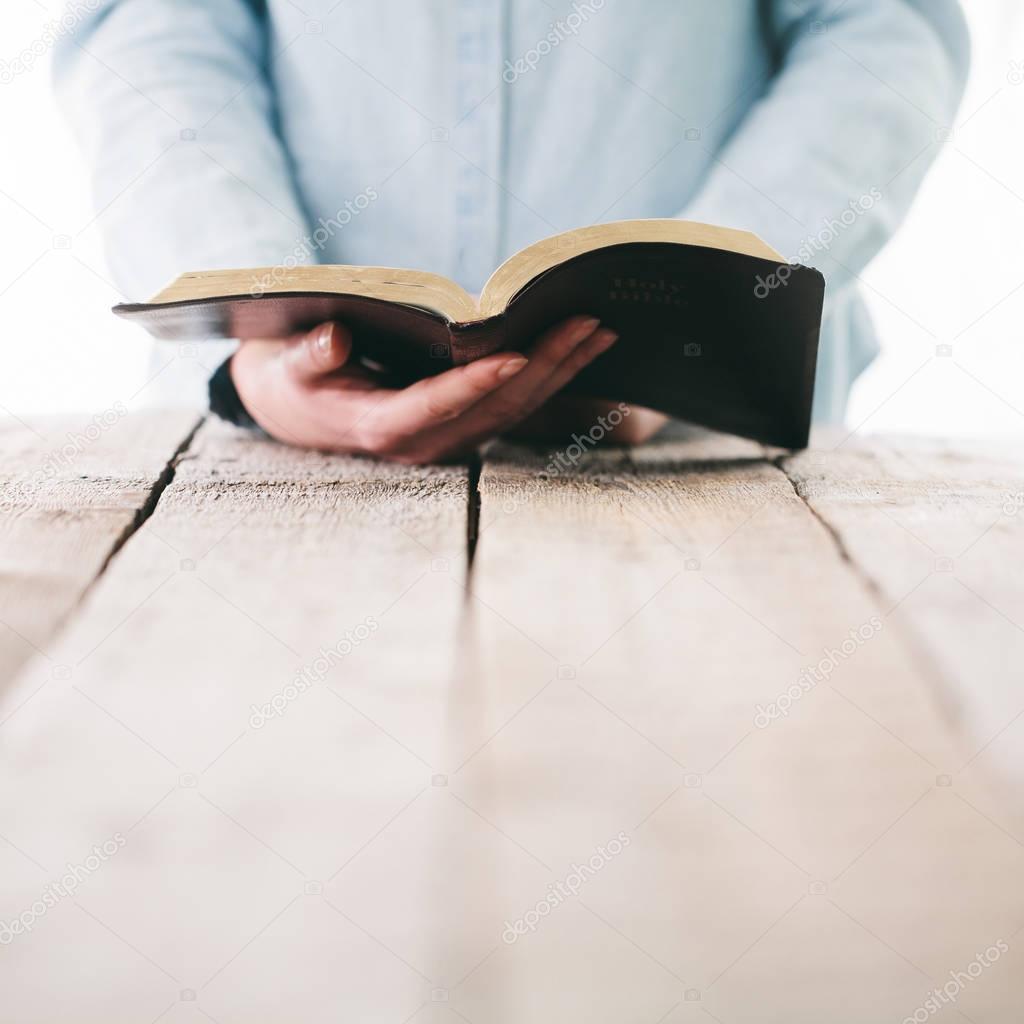 Bible in hands of a woman. She is readind and praying over it