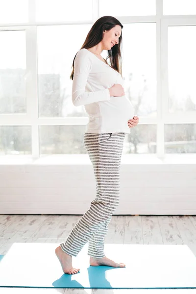 Mulher grávida em casa andando e segurando barriga — Fotografia de Stock