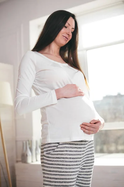 Беременная женщина дома ходит и держит живот — стоковое фото