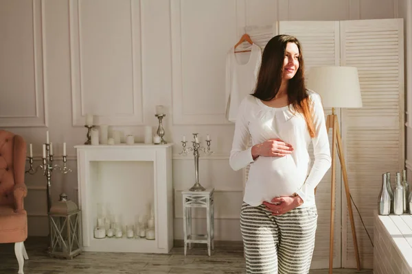 Kobieta w ciąży w domu spaceru i przytrzymując brzuch — Zdjęcie stockowe