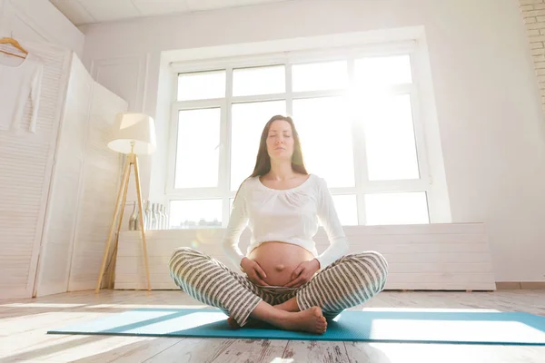 Mujer embarazada haciendo yoga en casa —  Fotos de Stock