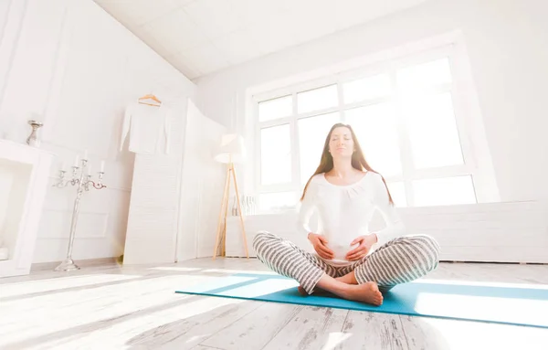 Gravid kvinna som gör yoga hemma — Stockfoto