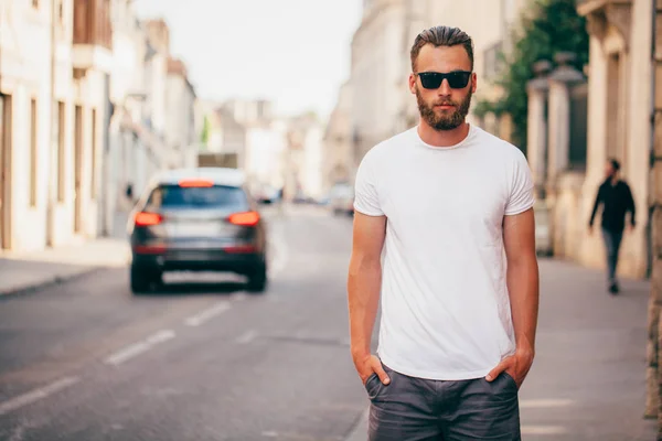 Hipster handsome male model with beard wearing white blank t-shirt with space for your logo or design in casual urban style — Stock Photo, Image
