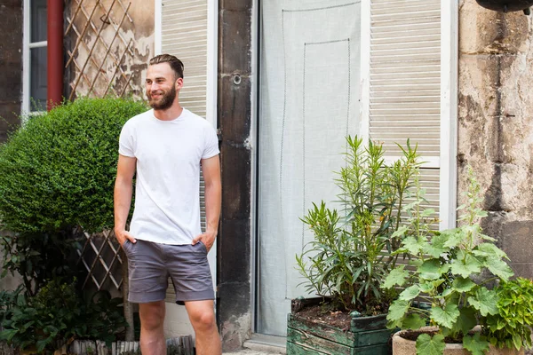 Hipster handsome male model with beard wearing white blank t-shirt with space for your logo or design in casual urban style — Stock Photo, Image