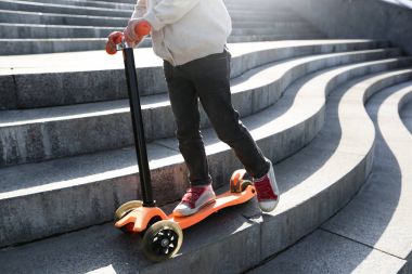 Şehirde scooter süren bir çocuk.