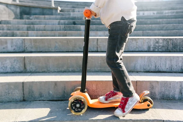 Criança montando uma scooter na cidade — Fotografia de Stock