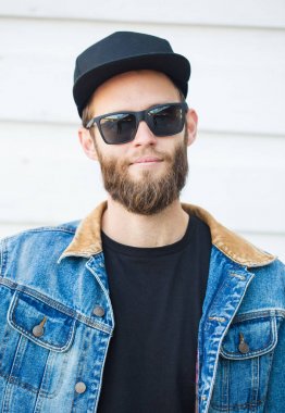 Modaya uygun kot elbise giyen gülümseyen yakışıklı hipster adam