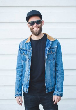 Modaya uygun kot elbise giyen gülümseyen yakışıklı hipster adam