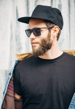 Modaya uygun kot elbise giyen gülümseyen yakışıklı hipster adam